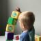 child at a nursery stacking blocks which are tipping